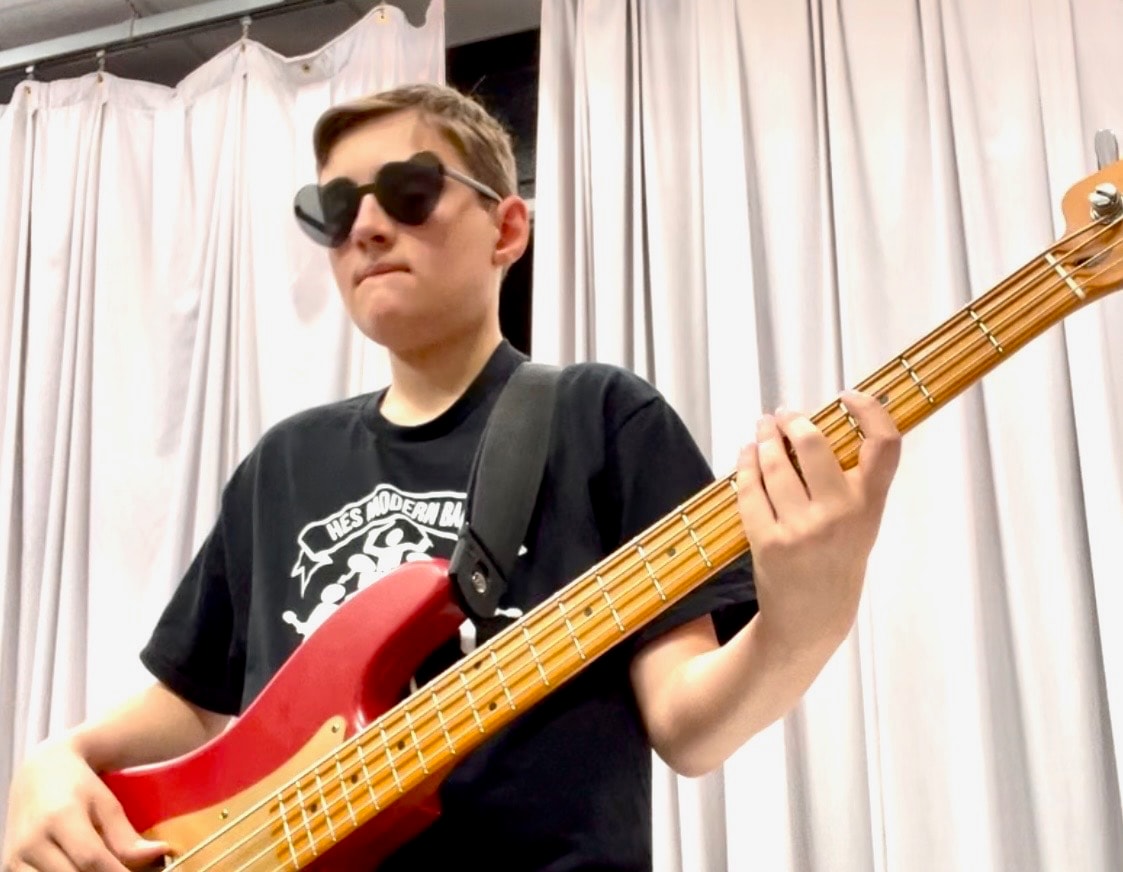 Musician playing red bass guitar indoors